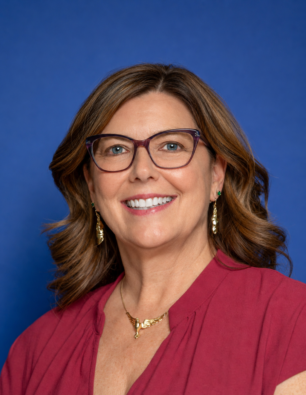 Womn with dark hair and glasses smiling 